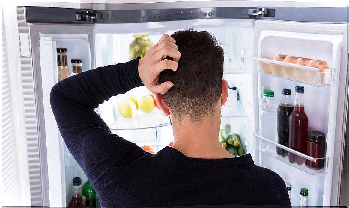 Man in front of open fridge suffering from anxiety about eating 