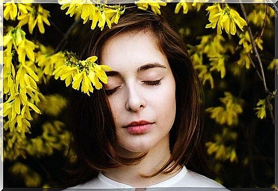 Girl under yellow flowers enjoying being good with oneself