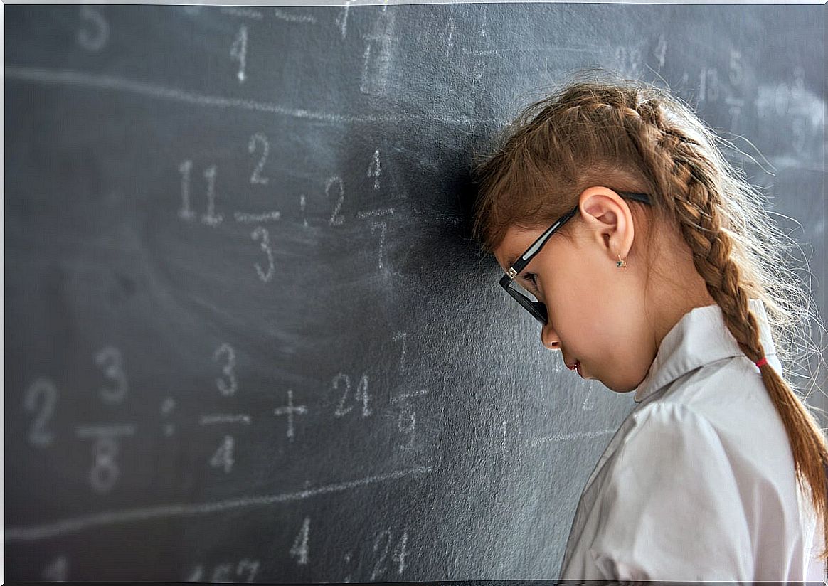 Schoolgirl leaning her head on the blackboard