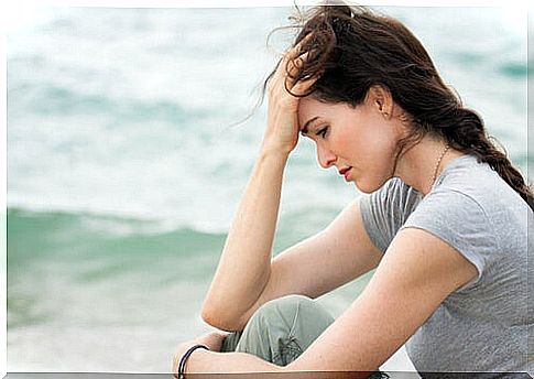 Woman sitting in front of the sea thinking that life is difficult