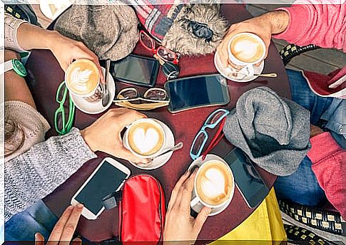 Group of friends drinking coffee with mobiles on the table