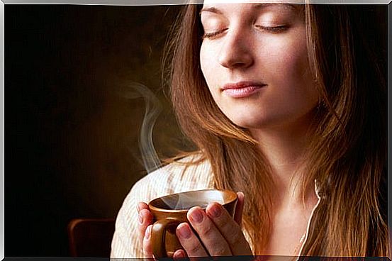 woman with cup in hand enjoying the smell of coffee