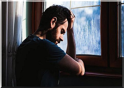 Man experiencing guilt while looking out the window