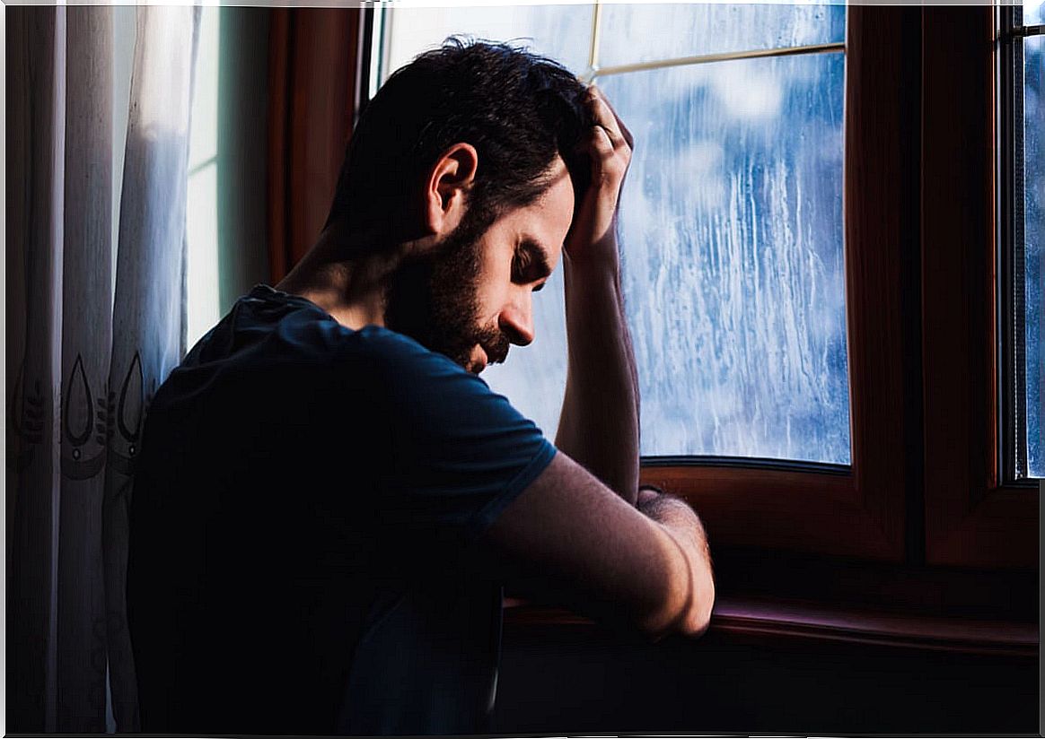 Sad man looking out the window thinking about why a loving couple separates